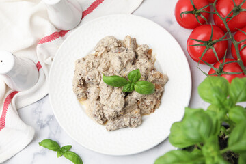 Tasty beef Stroganoff with basil and tomatoes on white marble table, flat lay