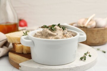 Tasty beef Stroganoff with thyme in casserole, bread and spices on white table, closeup