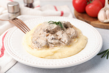 Delicious beef stroganoff with mashed potatoes and rosemary served on light table, closeup