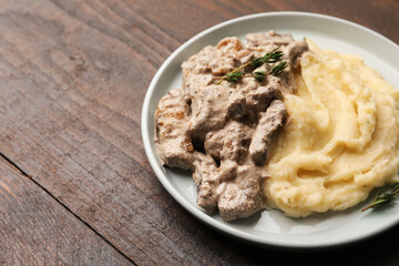 Delicious beef stroganoff with mashed potatoes and thyme on wooden table, closeup. Space for text