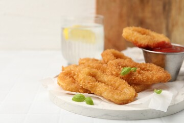 Deep fried squid rings with basil and ketchup on white tiled table, closeup. Space for text
