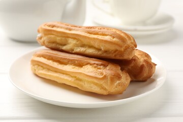 Fresh tasty eclairs on white wooden table, closeup