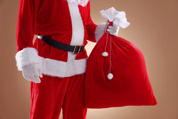 Santa Claus holding sack on beige background, closeup. Merry Christmas and Happy New Year