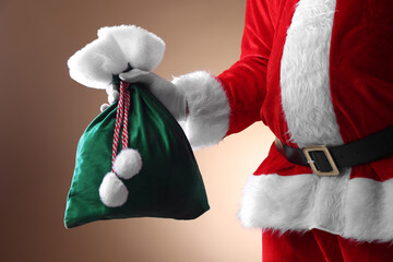 Santa Claus holding sack on beige background, closeup. Merry Christmas and Happy New Year