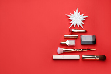 Christmas tree made with makeup products and brushes on red background, flat lay. Space for text