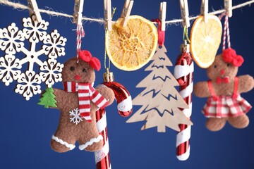 Naklejka premium Different Christmas decor hanging on string against blue background, closeup. New Year greeting card