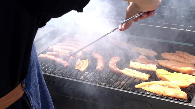 Man grilling meat on an outdoor barbecue. Leisure time with friends