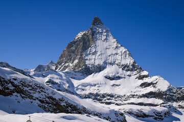 Close view of the Matterhorn covered in winter snow, rising sharply under a deep blue sky. Iconic Swiss alpine landscape with dramatic textures and prisitine mountain scenery.