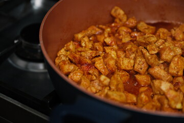 Close up of cubed chicken cooking in a boiling broth in a copper colored pot