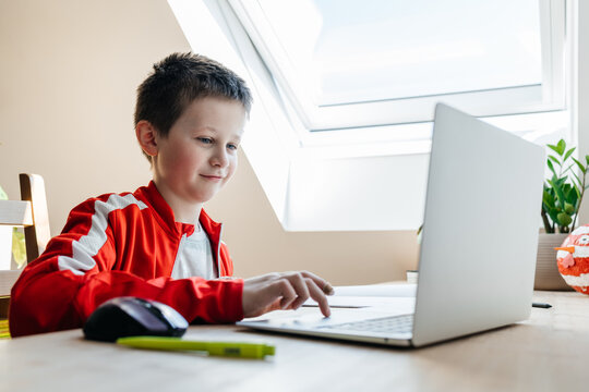 Young boy learning online using laptop at home