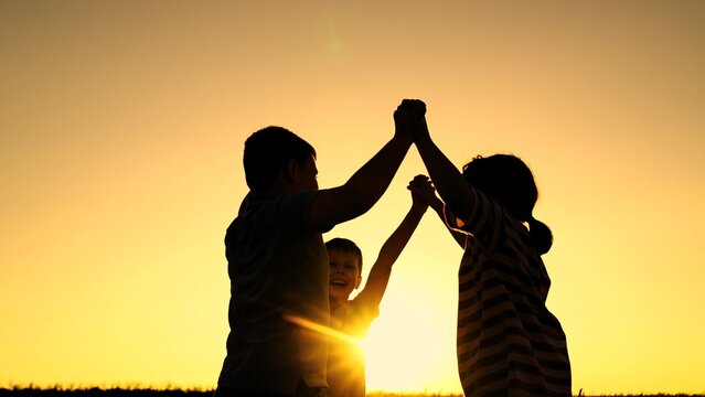 Kids boys girl raise hands to sky, rejoice, laugh, silhouette. Children team of winners plays in park in summer. Kids raise hands to sky. Children teamwork. Children laugh have fun in sun. Teenagers - Powered by Adobe