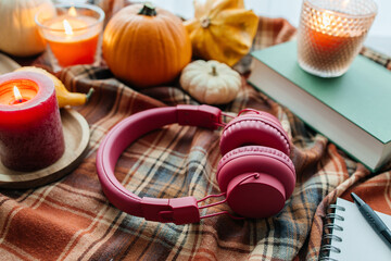 Autumn mood with headphones, book, candles, and plaid blanket