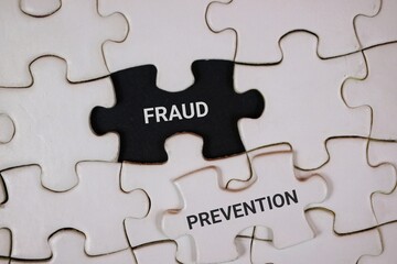 Fototapeta premium white puzzle pieces with an black center piece labeled FRAUD and an adjacent white piece reading PREVENTION, symbolizing awareness, detection, and proactive safeguards in business security.