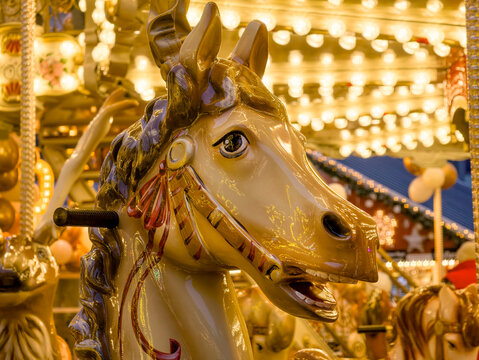 Carousel horse head closeup at illuminated fairground with warm vintage lights