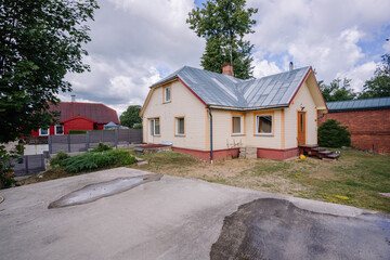 Fototapeta premium Charming residential house with a sloped roof, surrounded by greenery and a concrete driveway, showcasing a peaceful suburban environment with inviting outdoor space