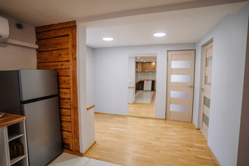 Modern kitchen interior featuring a sleek refrigerator, wooden accents, and open layout, showcasing contemporary design elements and inviting atmosphere for culinary activities