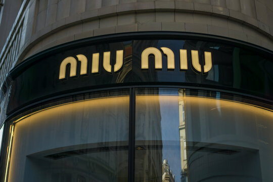 Vienna, Austria, Europe - Nov 08, 2025: Miu Miu store sign with illuminated curved letters on a corner glass facade