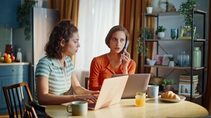 Calling brunette sitting friend at home kitchen looking laptops. Serious woman