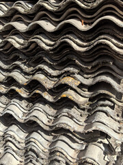 Wavy layers of weathered roofing material stacked in natural sunlight