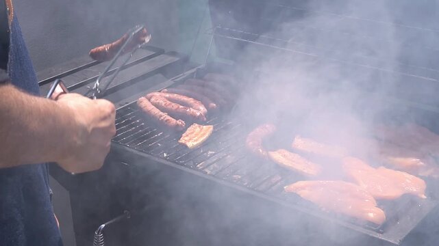 Man grilling meat on an outdoor barbecue. Leisure time with friends