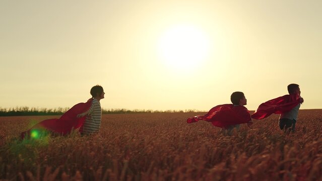 Kids in cape play heroes. Happy children run play superheroes in nature. Children boy girl play superhero in red cape on wheat field, children dream. Child hero in red cape run into sunset. Carnival - Powered by Adobe