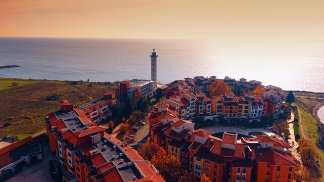 Stunning bright buildings in Marina Cape complex with beautiful lighthouse. Vast Black Sea waterscape dazzled by the setting sun. Aerial view.