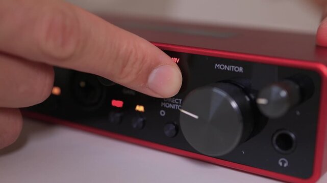 Adjusting external sound card knob, Precise control over audio output through knob rotation, Modifying sound levels using detailed textured dial on external audio interface