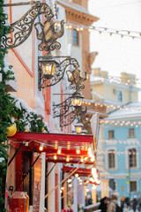 Cozy winter street view with building facades, snow, and illuminated lanterns