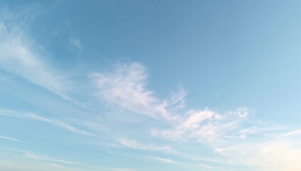 A soft blue sky with wispy white clouds scattered across the frame on a bright and sunny day scene