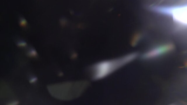 Lens Flare, abstract bokeh lights moving. Leaking Reflection of a Glass, Crystal, Defocused Shining Colorful rainbow Light Leaks, Rays on Black Background 