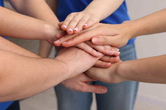 Team of volunteers stacking hands on grey background, closeup - Powered by Adobe