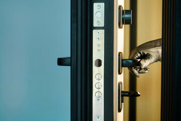 Hand in black leather glove opening armored door handle. Concept of illegal squatter, okupas, burglary, and thief entering house without leaving fingerprints. Photo