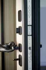 Hand in black leather glove opening armored door from inside. Concept of illegal squatter, okupas, burglary, and thief entering house without leaving fingerprints. Photo