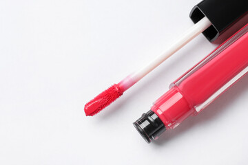 Beautiful lip gloss with applicator on white background, top view. Space for text