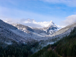 Obraz premium Snowy Mountain Range Over Foggy Valley in Winter Forest, British Columbia, Canada