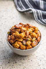 Nuts coated in sugar glaze in bowl on kitchen table.
