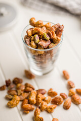 Nuts coated in sugar glaze in jar on white table.