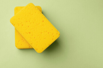 Kitchen sponges on light green background, top view. Space for text