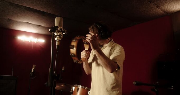 Professional musician playing tambourine in recording studio