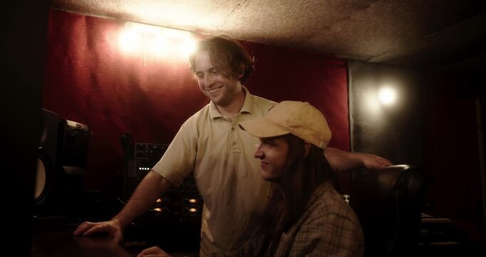 Sound engineers collaborating and laughing in music recording studio