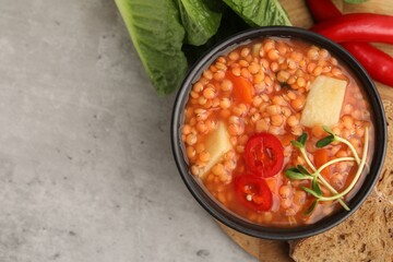 Delicious lentil soup with vegetables served on grey table, flat lay. Space for text