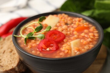 Delicious lentil soup with vegetables served on table, closeup