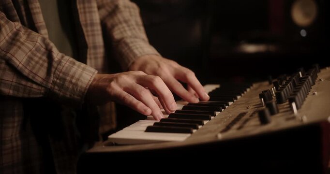 Musician hands playing synthesizer in recording studio