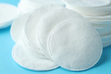 Clean cotton pads on light blue background, closeup