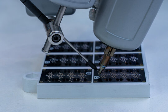 Advanced industrial robotic arm precisely soldering components onto array of dark printed circuit boards, showcasing automation and intricate detail in electronics manufacturing