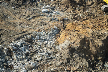 Detailed overhead view of chaotic construction site with excavated earth, concrete rubble, rebar, and distinct heavy machinery tracks on textured ground