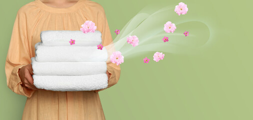 Woman holding fresh, pleasantly scented towels on light green background, closeup. Flows of aroma...
