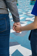 Closeup of couple on city mosaic tiles, Casual couple holding hands amidst textured urban environment, Intimate partners in casual clothing connecting during candid city walk