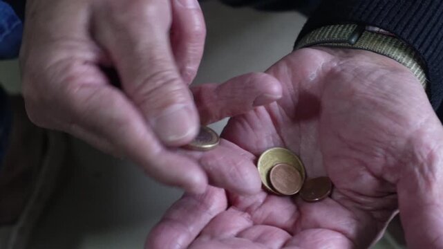Elderly man counting euro coins in his hands