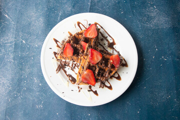 Delicious waffles topped with fresh strawberries and luscious chocolate sauce for a sweet treat and...